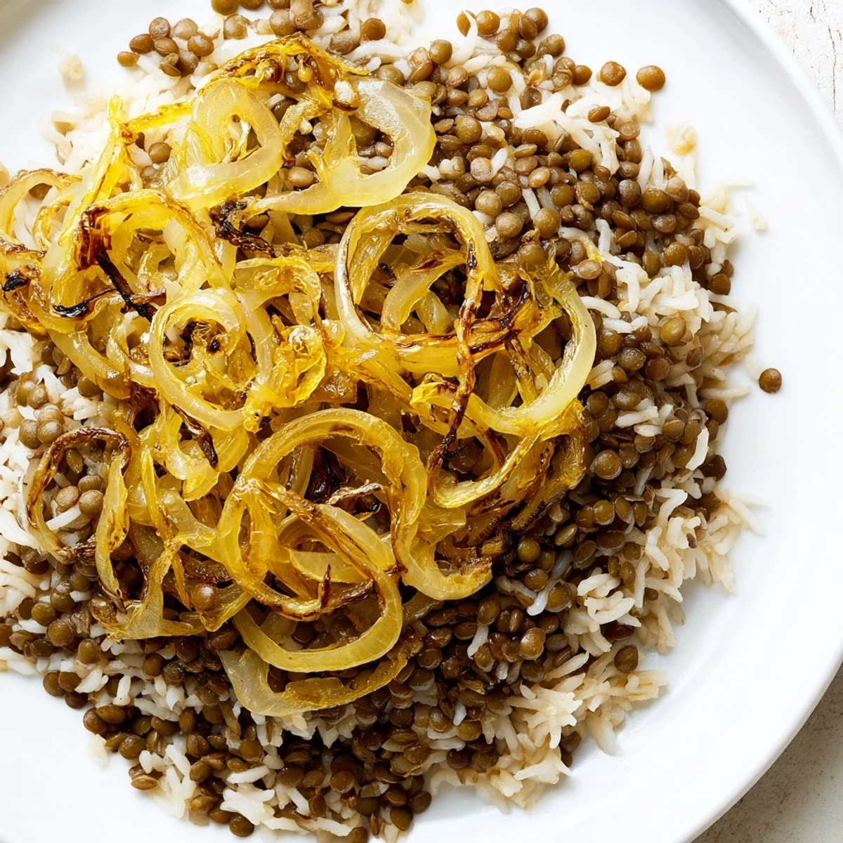 Steaming Lebanese Mjadra, a hearty lentil and rice dish, topped with sweet, golden caramelized onions.