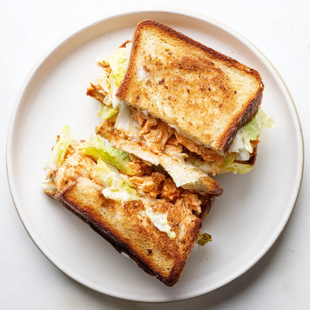 Golden-brown Buffalo Chicken Caesar Grilled Cheese on sourdough, with melted provolone and shredded romaine.  
