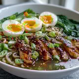 Healthy Miso Chicken Noodle Bowls in a steaming savory broth topped with soft-boiled eggs and sesame seeds.