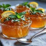Colorful Gummy Bear Lemonade Jelly Cups topped with mint leaves and lemon slices for a summer treat.  