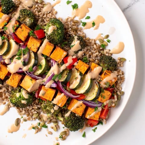 A steaming bowl of hearty roasted vegetable and farro grain bowl, topped with fresh parsley and crunchy seeds.