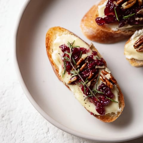 Toasted baguette slices with melted Brie, cranberry sauce, a delicious Festive Holiday Cranberry and Brie Crostini.