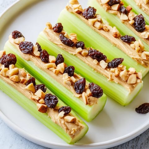 Close-up of vibrant peanut butter celery sticks: showcasing a fun snack with raisins and peanut topping.