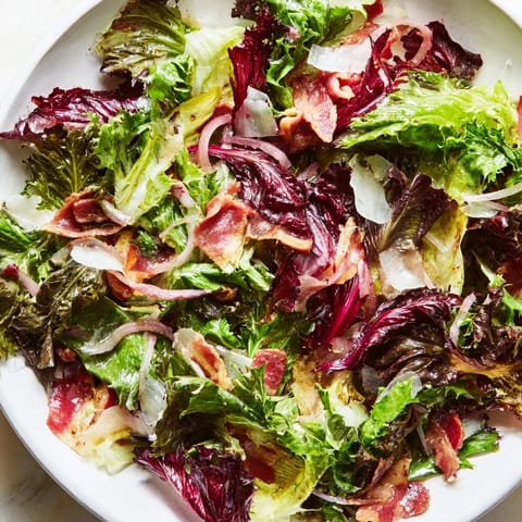Golden bacon bits top the fresh Bitter Greens Salad with Warm Bacon Dressing, ready to serve.