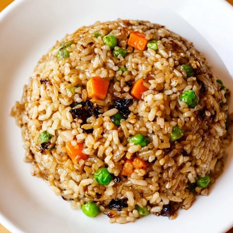 A close-up of Black Garlic Fried Rice showcases tender eggs, scallions, and a steamy, aromatic Asian fusion dinner.