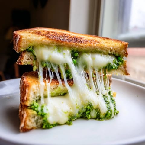 A close-up view shows the grilled cheese oozing with melted cheese, served warm on a plate with fresh basil garnish.