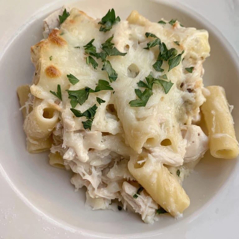 Golden-topped Chicken Alfredo Bake, revealing a cheesy, pasta casserole with tender chicken and rich sauce.