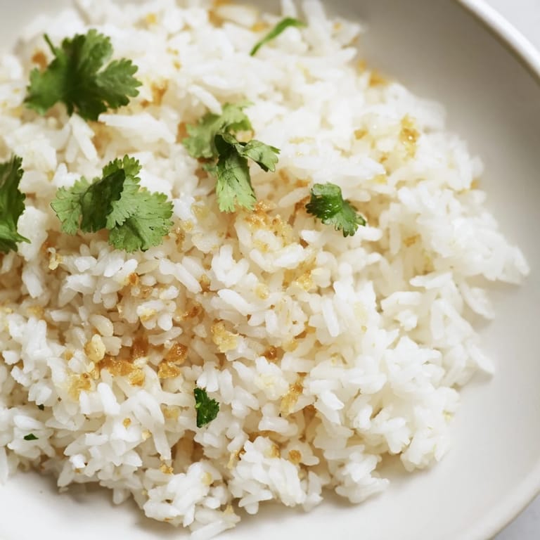 Steaming white jasmine rice with minced garlic and fresh cilantro, ideal for Asian-inspired meals.  