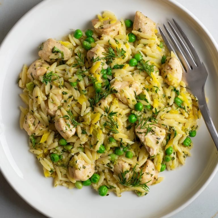 One-pan Lemon Herb Chicken Orzo Skillet featuring juicy chicken thighs, al dente pasta, and sweet peas in a savory Mediterranean-inspired sauce, ready to serve.