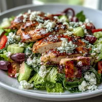 Vibrant Greek salad bowl with grilled chicken, fresh vegetables, and creamy feta, perfect for a healthy summer meal.  