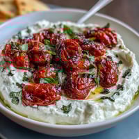 Creamy whipped feta dip topped with sweet roasted cherry tomatoes and fresh basil, served with warm pita bread.
